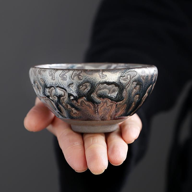 Oni tea cup resting on an open hand, showing a broad rim above its narrower standing foot