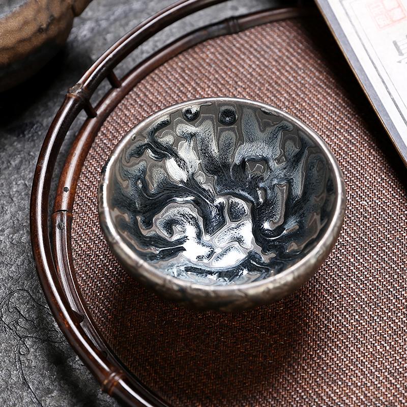 Empty Oni tea cup on a broad woven tray beside a book, with open space around the cup
